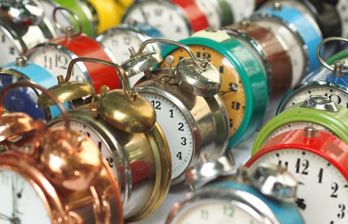 Several colorful old-fashioned alarm clocks, arranged diagonally