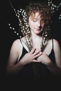 Kelly Todd poses with plants against a black background