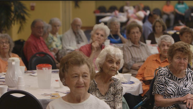 A still of elders in a room listening from "A Greater Society"