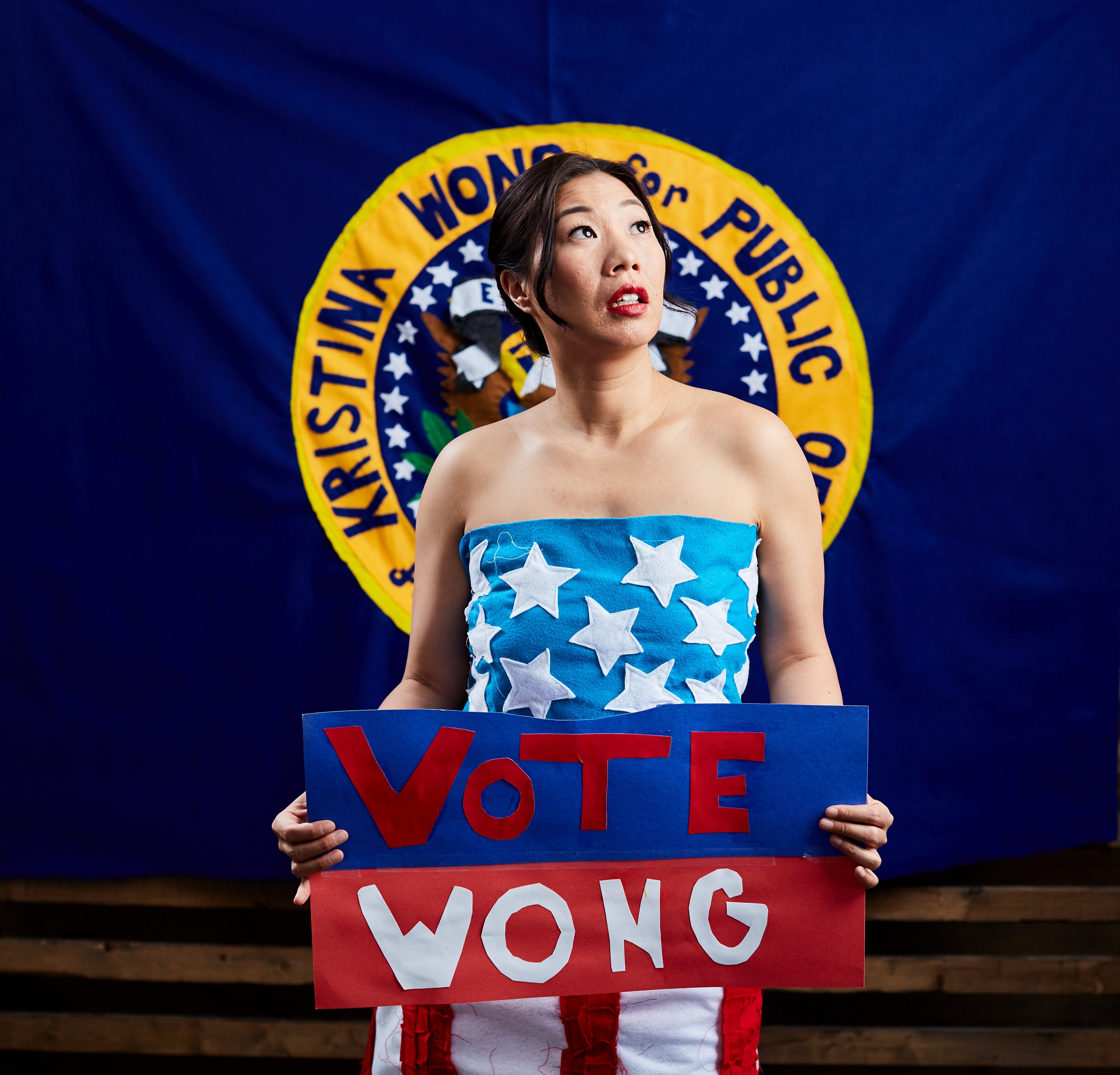 Kristina Wong with blue background and painted faux political seal Photo by Tom Fowler