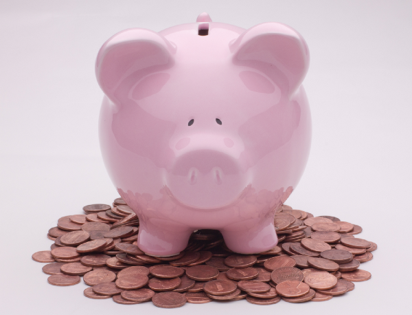 A piggy bank standing on top of a pile of pennies.