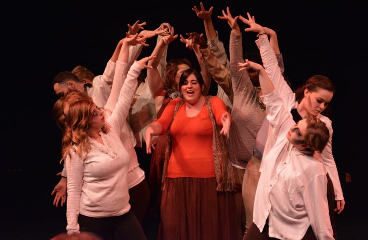 Jamie singing in center of 4 dancers on each of her sides with hands raised