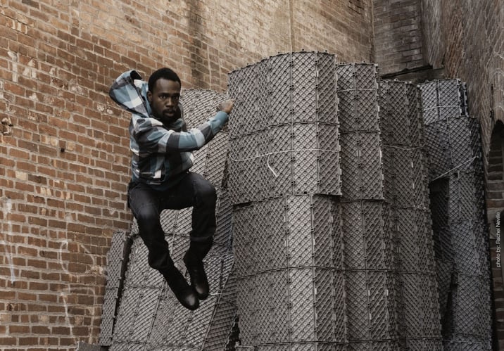 Andre dances, hanging in mid-air with brick background