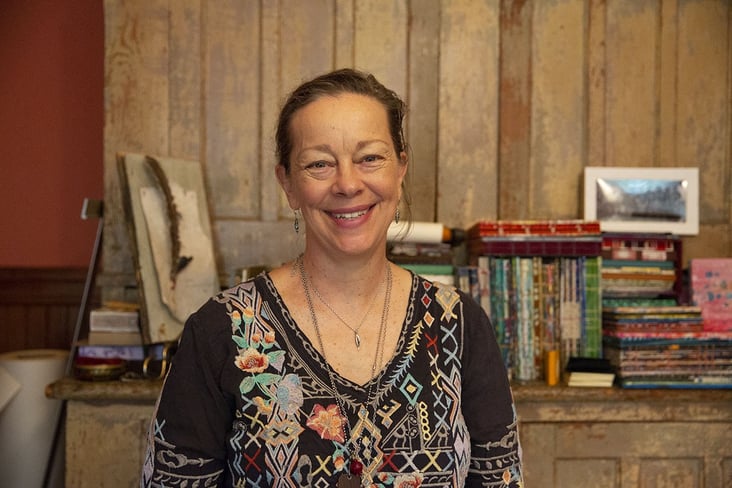 Suzi Banks Baum smiles with book collection in background