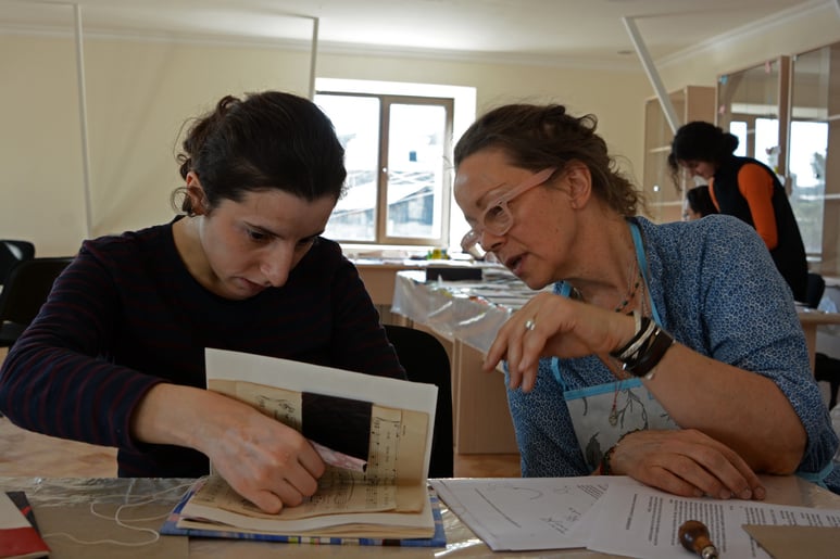 Suzi works with one a woman on a book collage project