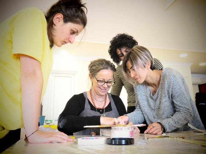 Suzi works on an art project with 3 women