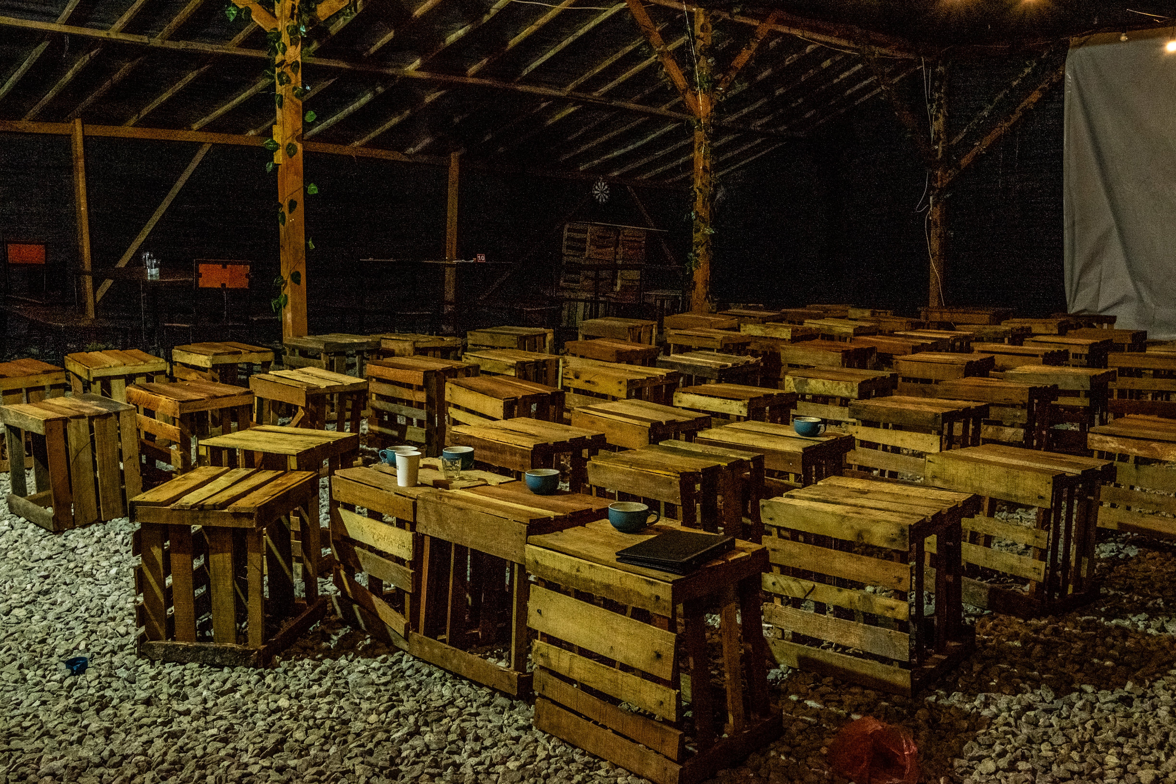 A group of wooden chair stools low to the ground that are empty. Some of them have used cups and mugs on them.