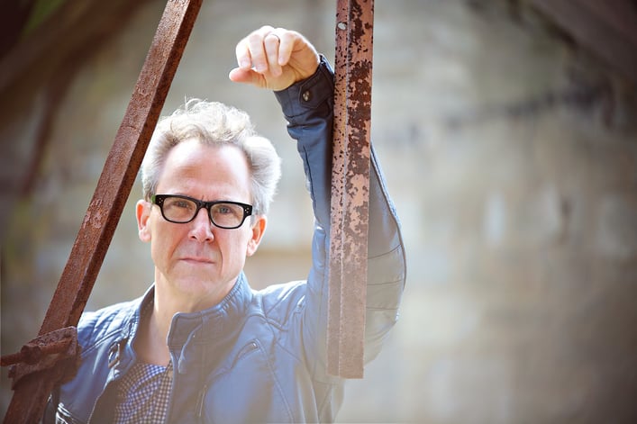 Zeke Zelker, creator of “Billboard," wearing glasses and blue vest