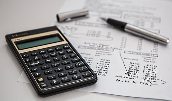 A calculator, pen, and financial document.