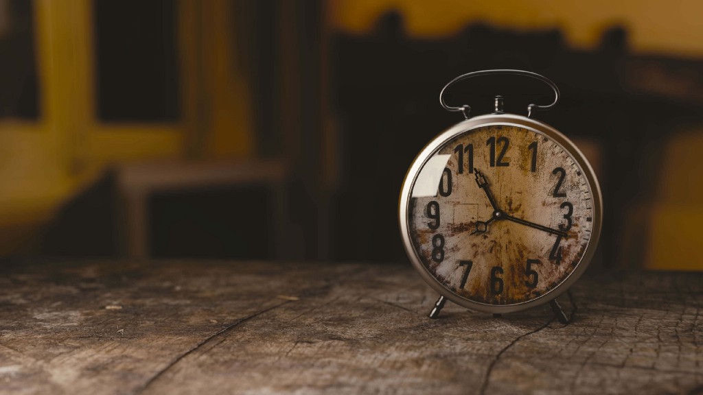 An antique clock sitting on a weathered wooden surface.