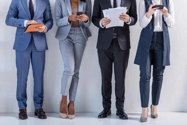 People standing in a row in suits considering whether or not virtual work suits them.