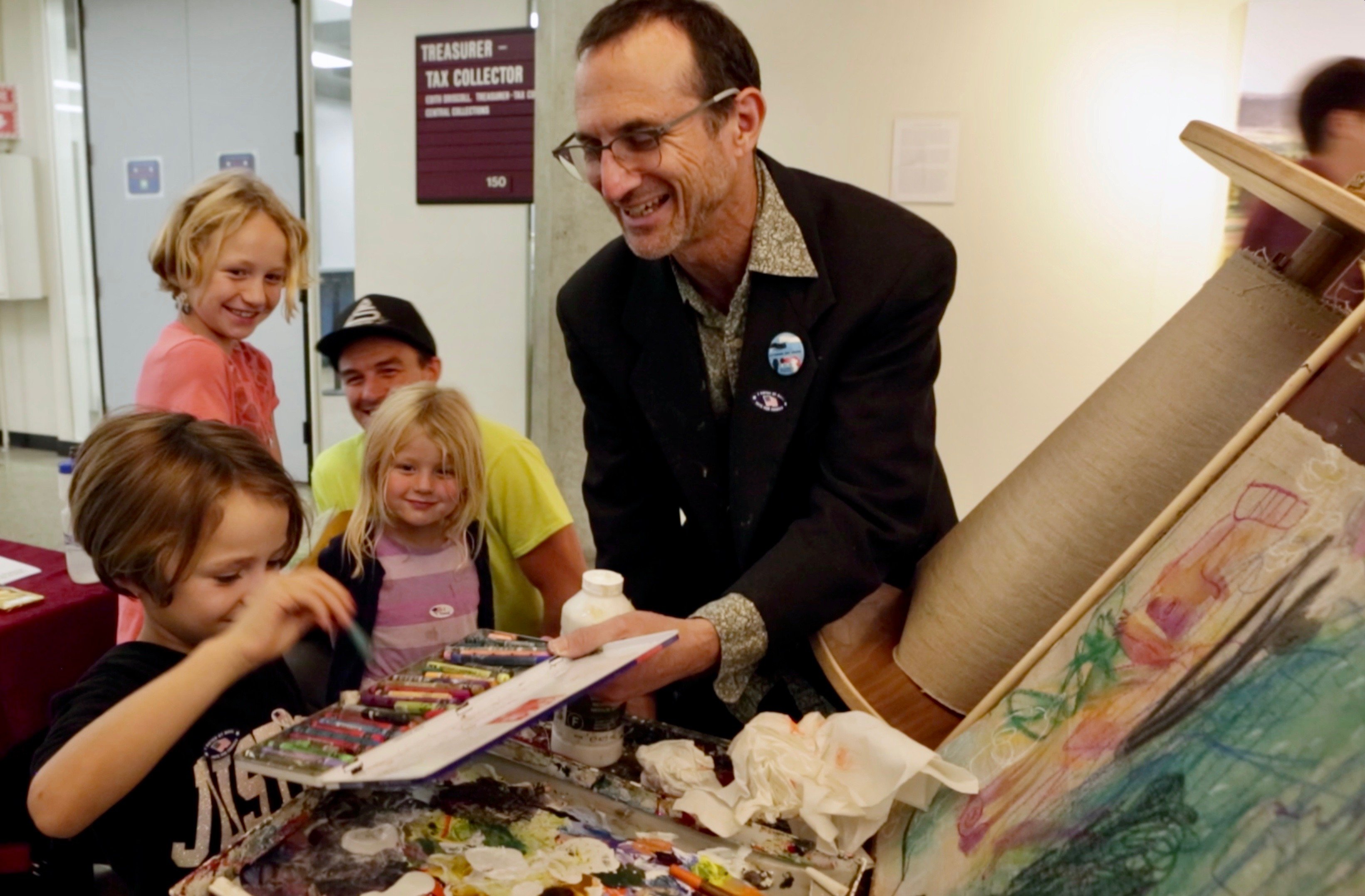 Andrew working on painting on The Curious Scroll with a family of 3 kids and a man