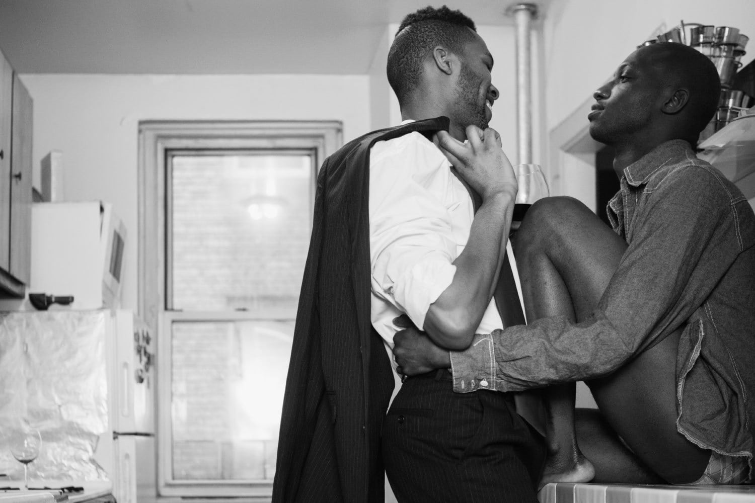 Two black men in love in a small kitchen about to kiss